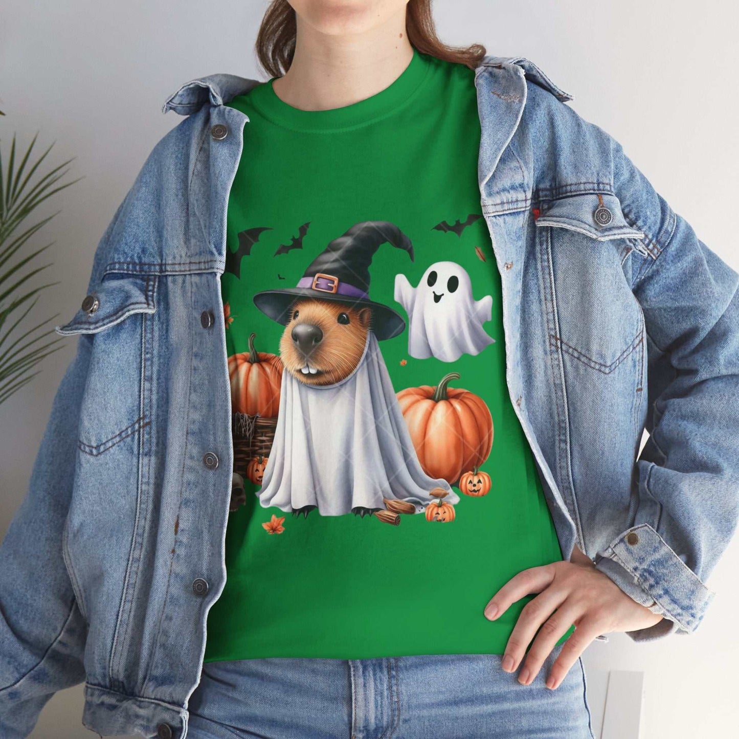 Woman wearing a green Halloween Capybara shirt with a spooky design featuring a capybara in a witch hat, pumpkins, and a ghost.
