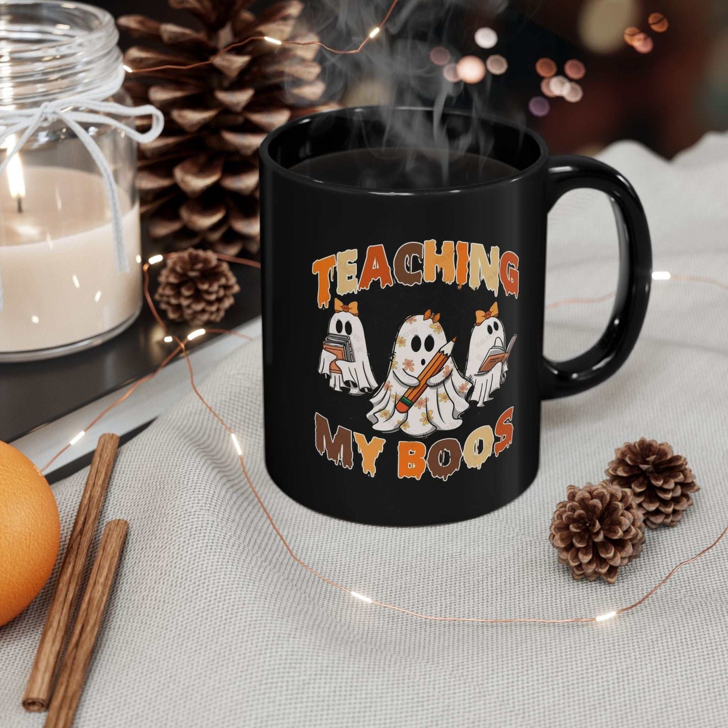 Comfort Colors Teaching My Boos Mugs is the ultimate cozy companion for spooky season.Black ceramic mug with "Teaching My Boos" design, featuring ghost illustrations for Halloween; perfect gift for teachers.