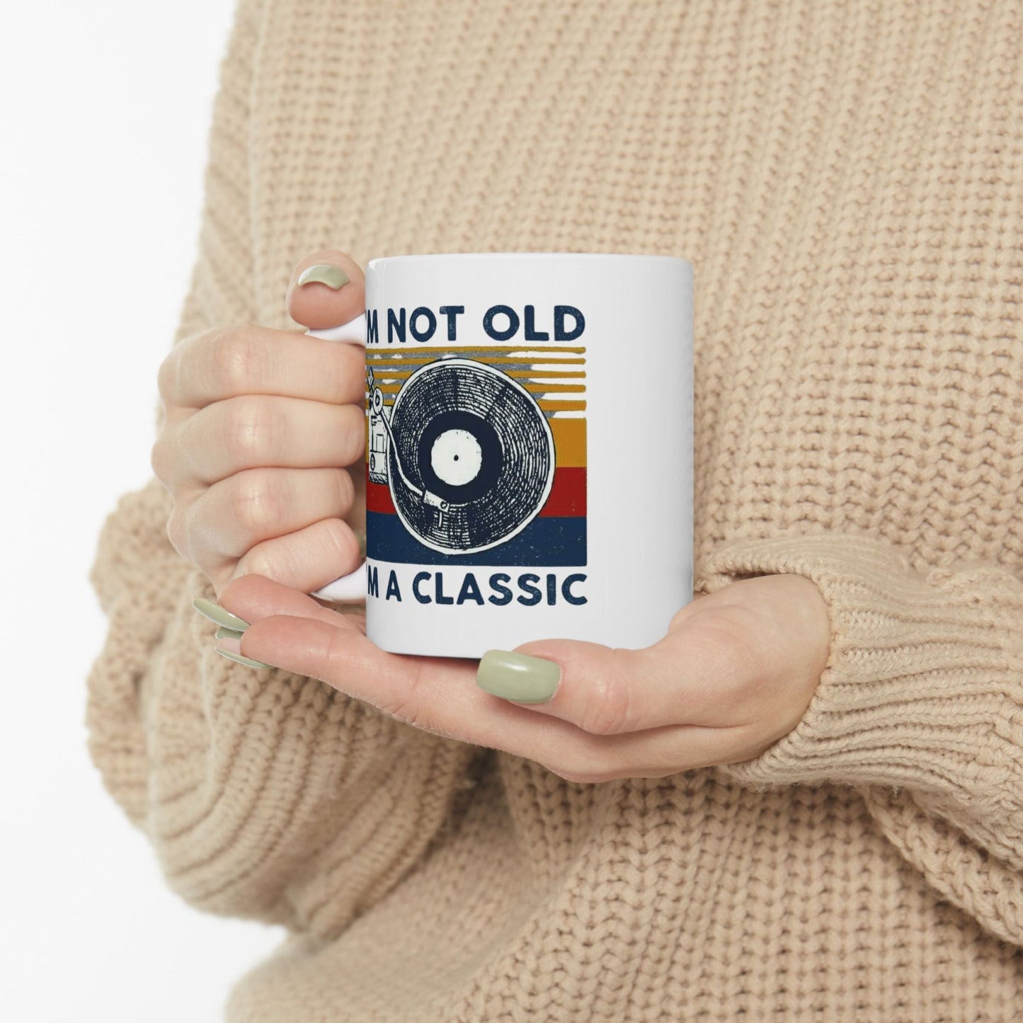 Vintage-inspired ceramic mug with "I'm Not Old, I'm A Classic" design held by a person wearing a cozy sweater.
