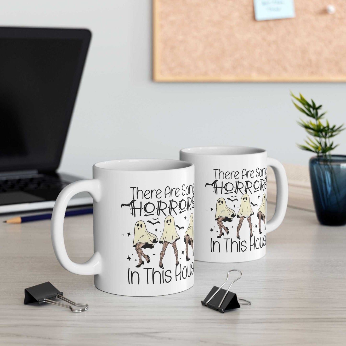 Funny Halloween mugs with ghost design on a desk setting, perfect for coffee lovers.