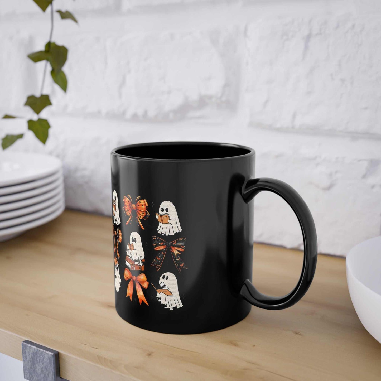 Black ceramic Halloween mug with ghost and book design, featuring a glossy finish and a comfortable C-shaped handle.