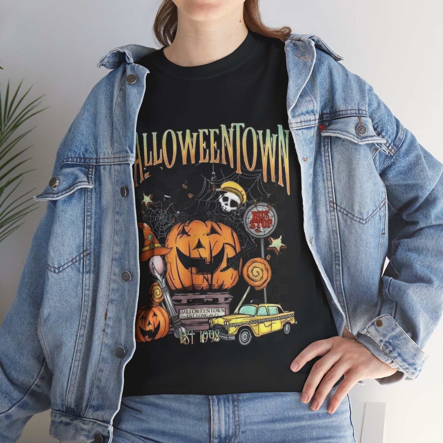 Woman wearing a Retro Halloweentown Shirt styled with a denim jacket, featuring festive Halloween graphics.