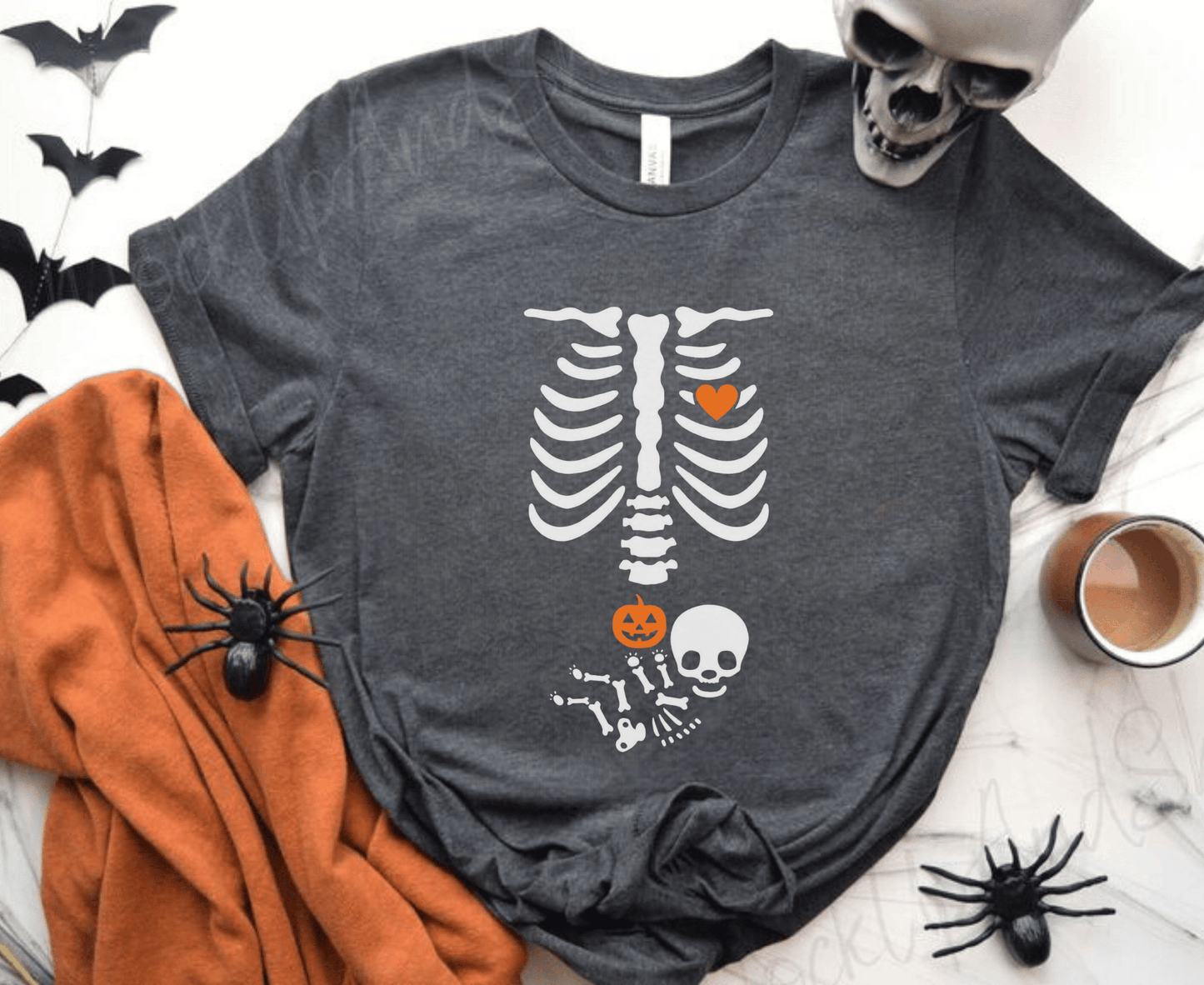Halloween maternity shirt with skeleton and pumpkin design.